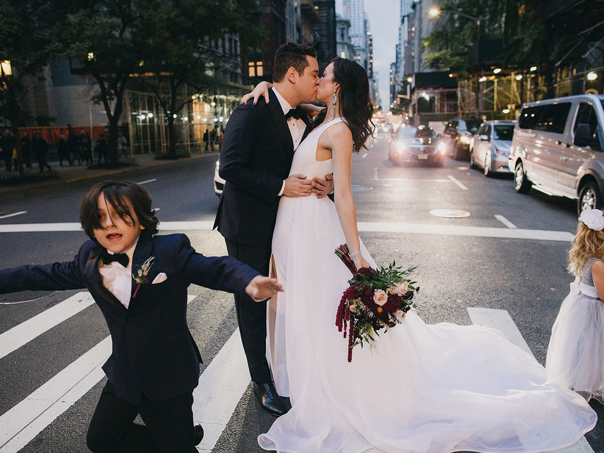 Newly wed couple kiss with flowers in hand